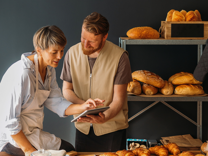 Zwei Personen in der Bäckerei am Tablet
